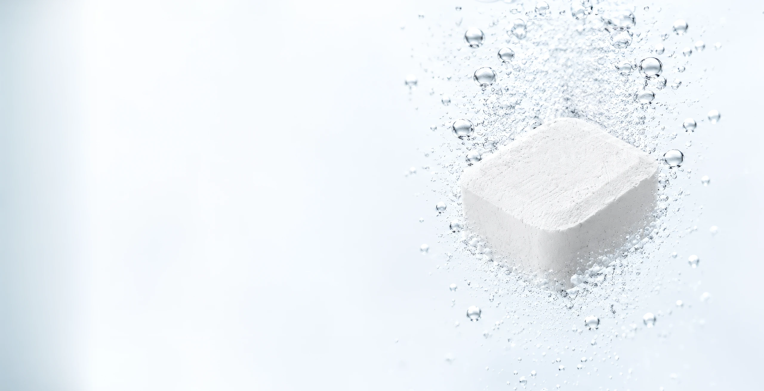 A single white cleaning tablet dissolving in clear water